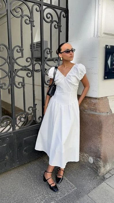 Mulher jovem e magra com, vestido midi branco e sapato boneca preto