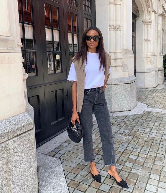 Mulher jovem e magra de pele escura. Ela usa look básico com calça jeans cinza.