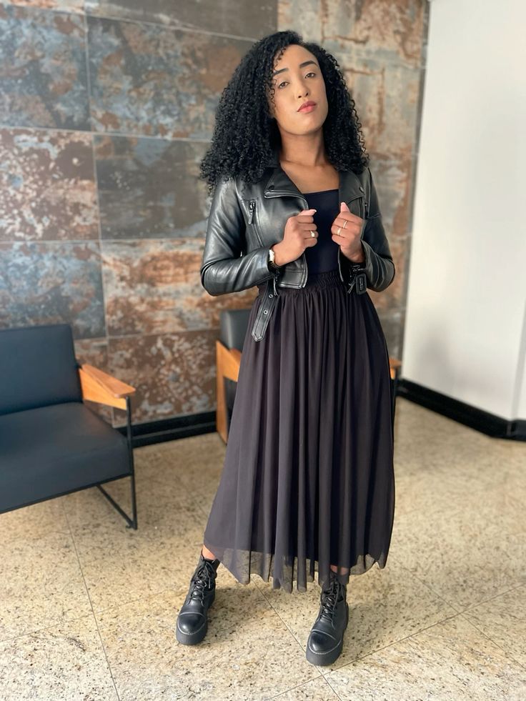 Mulher jovem, magra e preta, com cabelo cacheado, usando jaqueta de couro, saia em tule e coturno