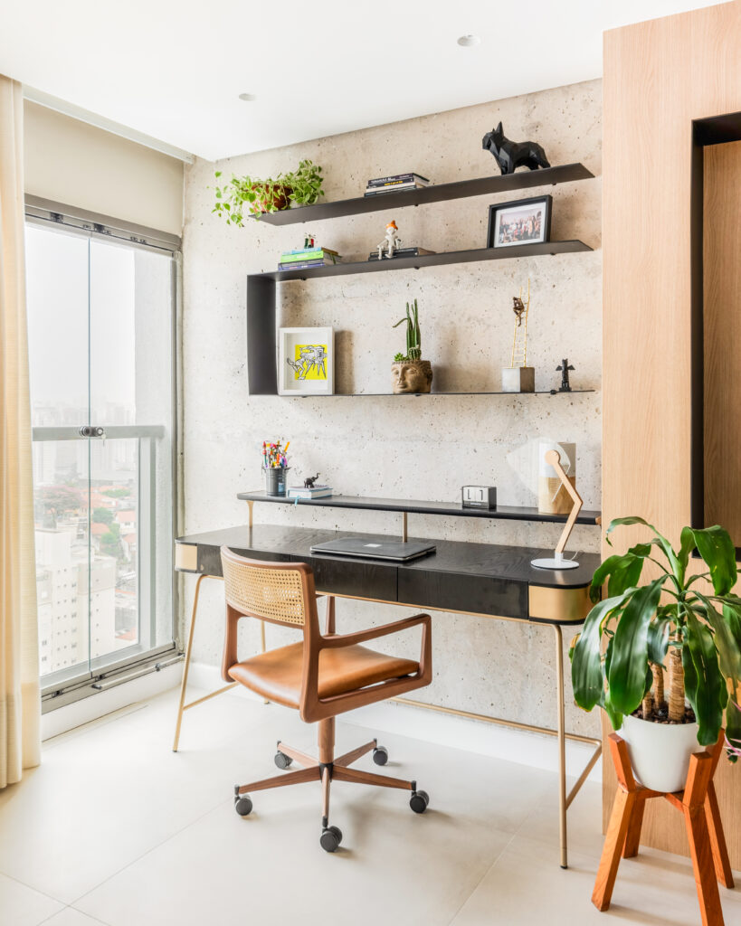 Home office com bancada e prateleiras pretas e cadeira de couro marrom