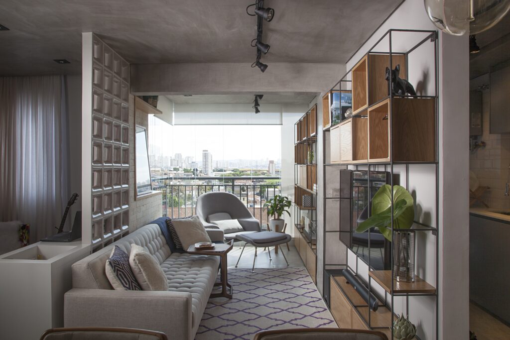 Sala de estar com com estante de metal e nichos de madeira, e cobogó de concreto