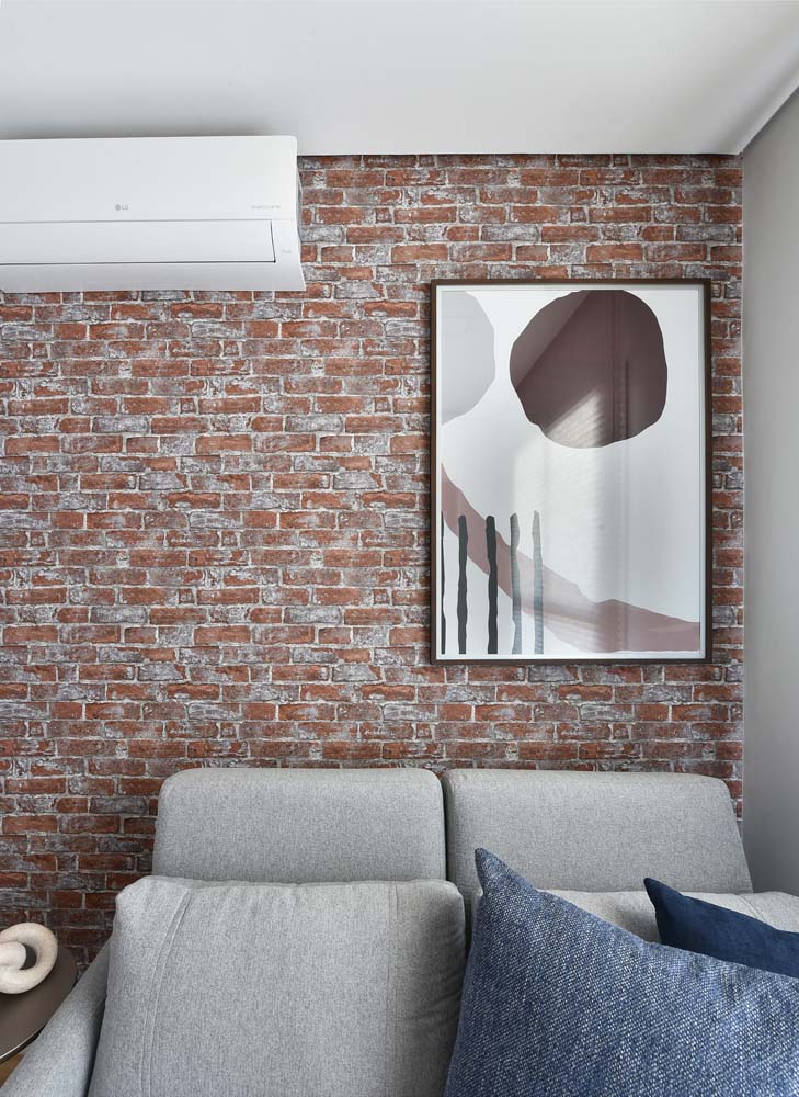 Sala com sofá-cama e papel de parede de tijolinhos