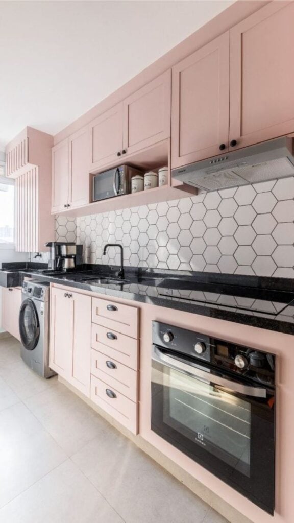 Cozinha rosa com detalhes em preto e bancada em granito escuro