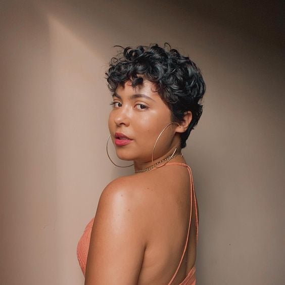 Mulher negra com corte de cabelo bixie cacheado e com franja