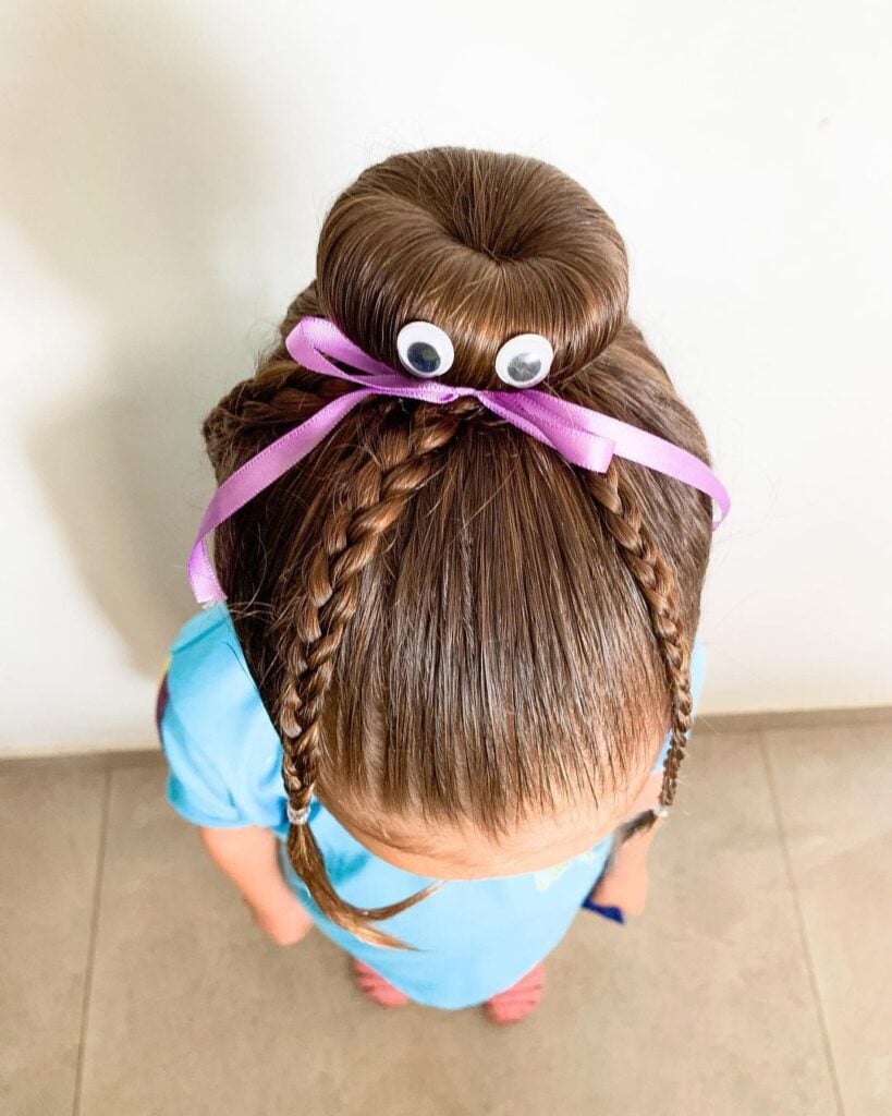 Menina com cabelo maluco de coque com olhos e laço lilás com tranças
