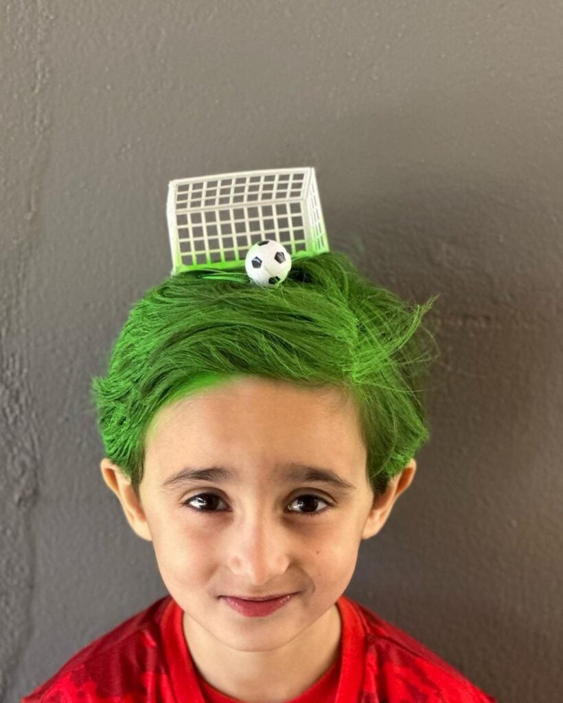 Menino com cabelo maluco, com goleira e bola de futebol