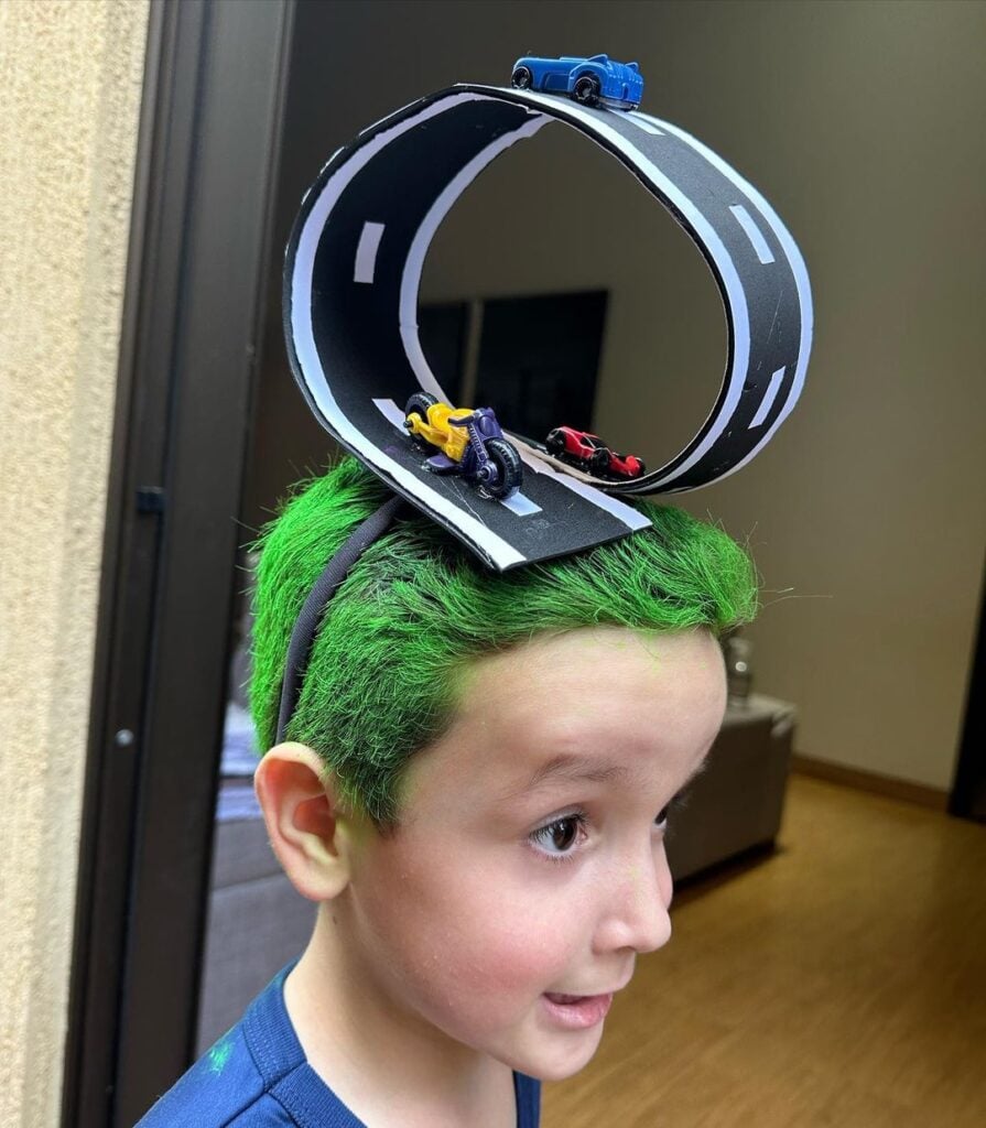 Menino com cabelo maluco, com pista, carros e moto