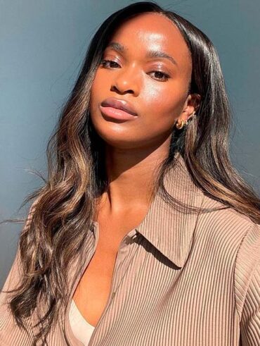 Mulher de pele preta, com cabelo escuro e casaco bege