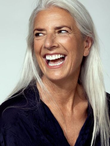 Mulher de pele branca e madura, cabelo branco, e blusa preta