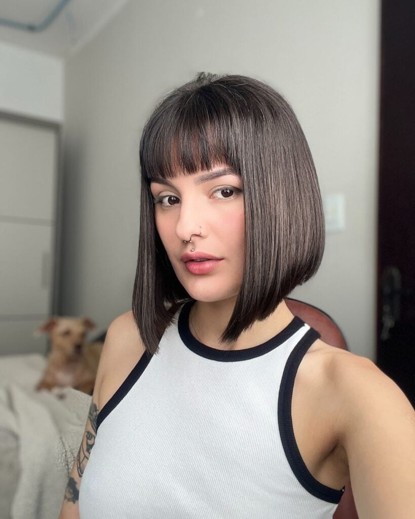 Mulher branca, com cabelo castanho, com corte curto, chanel e com franja