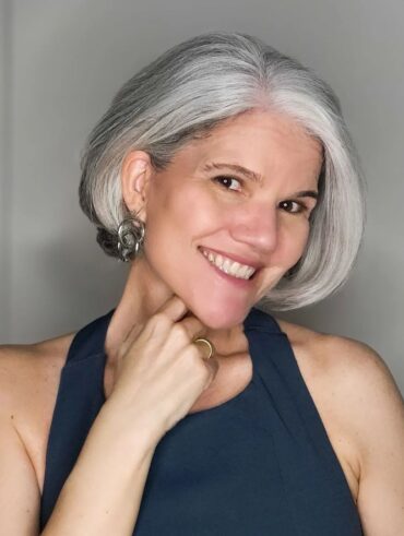 Mulher de pele branca, com regata preta, cabelo curto grisalho e pele madura
