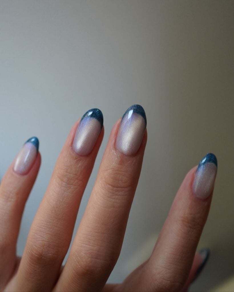 Mão de pele branca com unha amendoada com francesinha azul magnética