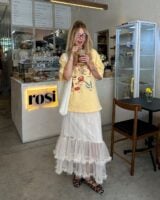 Julia com camiseta estampada, maxi bag branca, saia midi de tule e sapatilha Mary Jane animal print