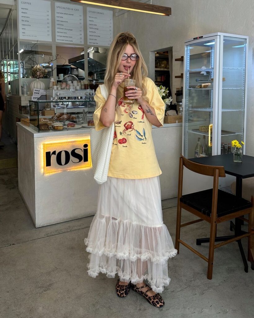 Julia com camiseta estampada, maxi bag branca, saia midi de tule e sapatilha Mary Jane animal print