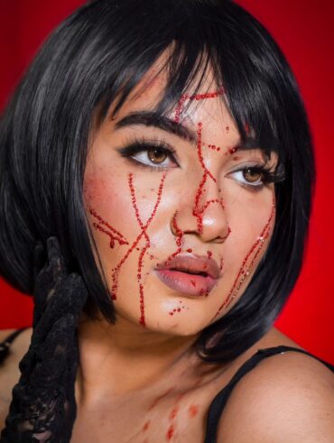 Mulher de pele branca, com peruca curta e morena e maquiagem de Halloween com strass