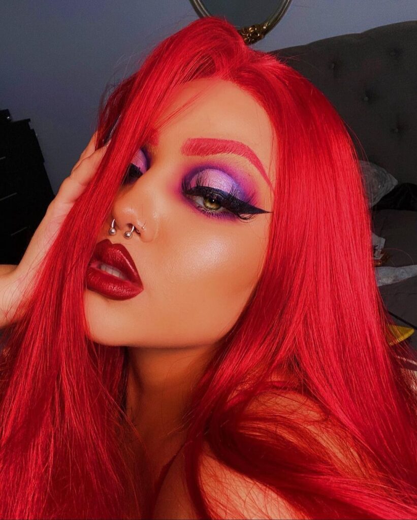 Mulher de pele branca, com peruca vermelha e maquiagem de Jessica Rabbit