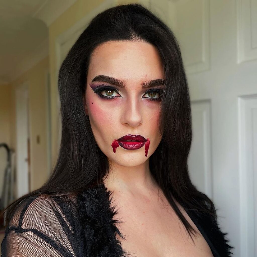 Mulher de pele branca, com cabelo escuro e maquiagem de vampira