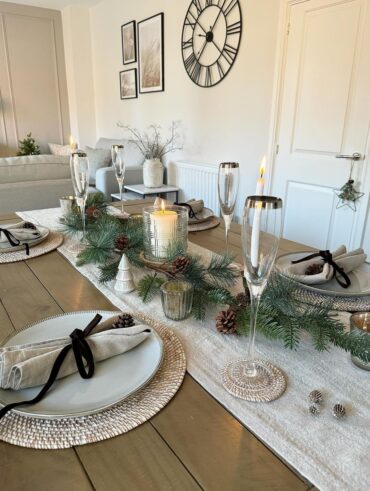 Mesa posta de Natal, com guardanapo decorado, pinhas e plantas
