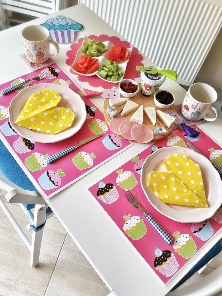 Mesa branca com jogo americano de cupcakes e guardanapos amarelos com bolinhas brancas