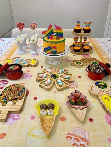 Mesa com toalha de cupcake e muitas guloseimas