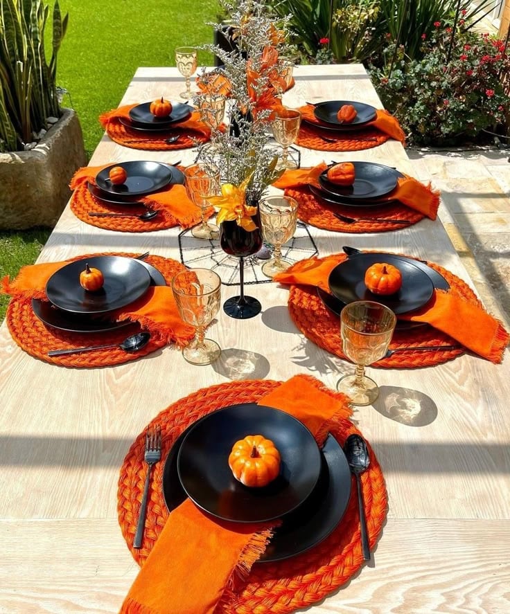 Mesa com sousplat laranja e louças pretas