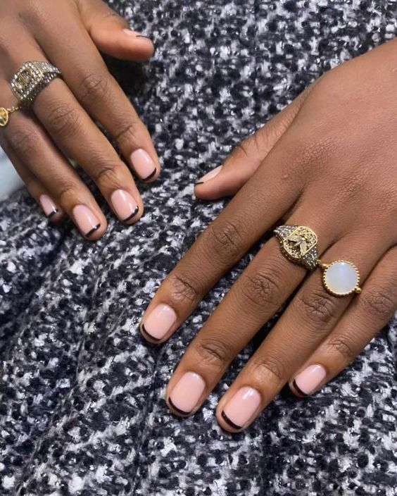 Mãos de pele preta, com anéis dourados e prata e unha com microfrancesinha preta