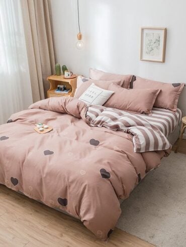 Cama com edredom em tons de marrom com corações e listras