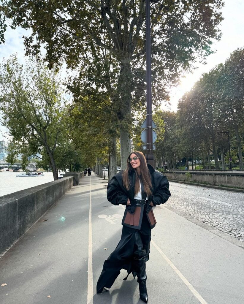 Bianca Andrade em rua de Paris, usando óculos de sol, jaqueta preta, saia preta com aberturas e bota de cano alto.
