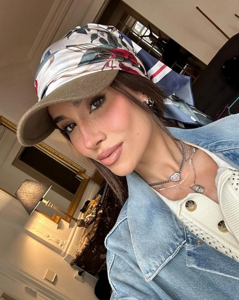 Bianca Andrade usando jaqueta jeans, mix de colares pratas, cabelo preso em boné com lenço.