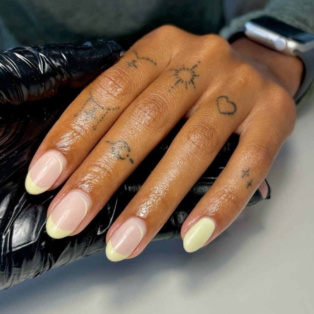 Mão de pele negra, com unha curta, com nail art usando esmalte amarelo-manteiga