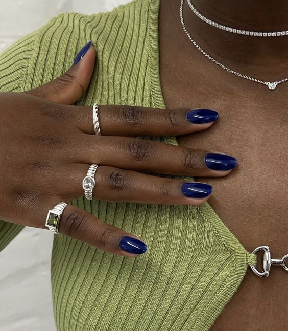 Mão de pele preta, com anéis em prata e unha amendoada azul-escuro 
