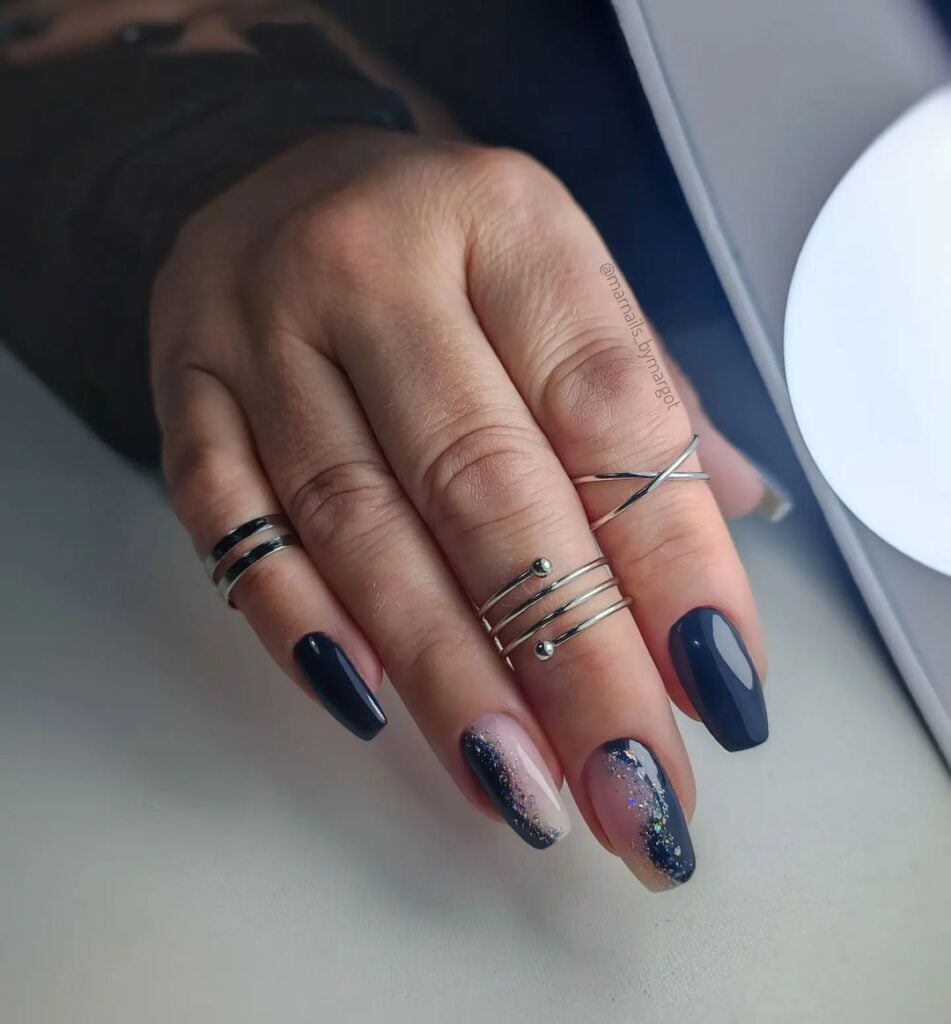 Mão de pele branca, com anéis prata e unha bailarina azul-marinho decorada
