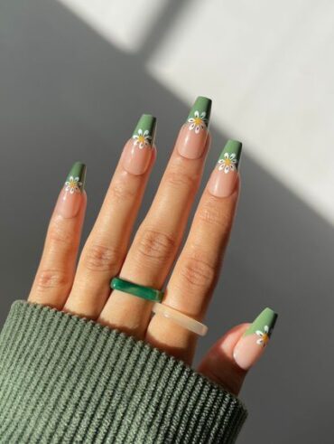Mão de pele branca, com anéis coloridos e unha bailarina com francesinha verde e flor