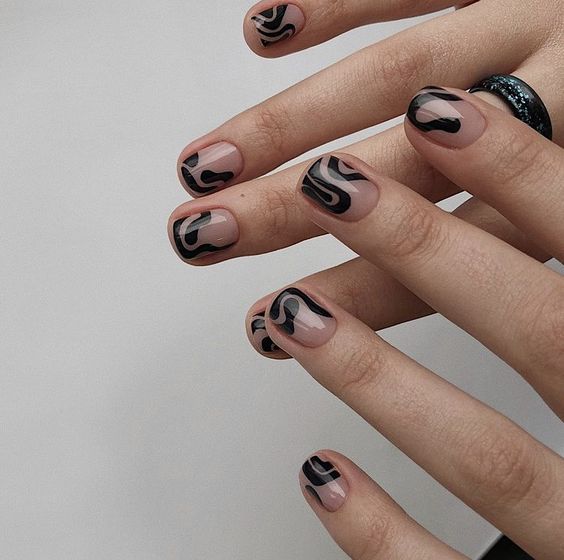 Mãos de pele branca com unha curta e quadrada com decorações orgânicas com esmalte preto