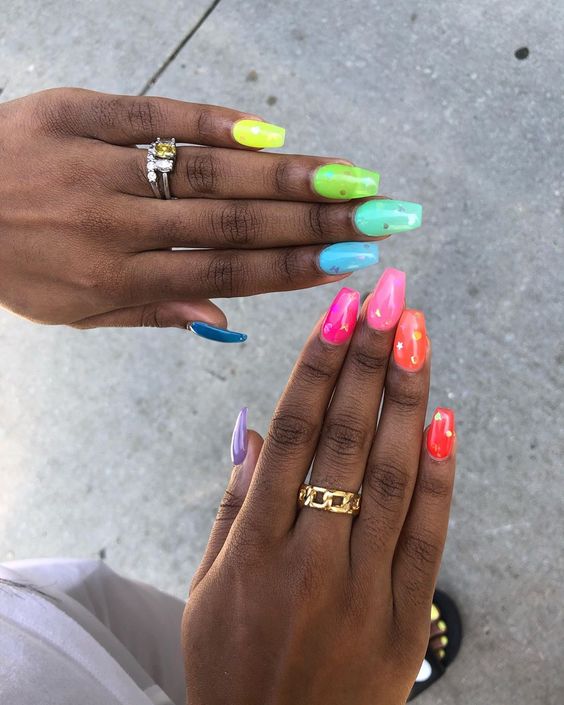 Mãos de pele preta, com anéis em prata e dourado e unha bailarina jelly colorida e decorada 