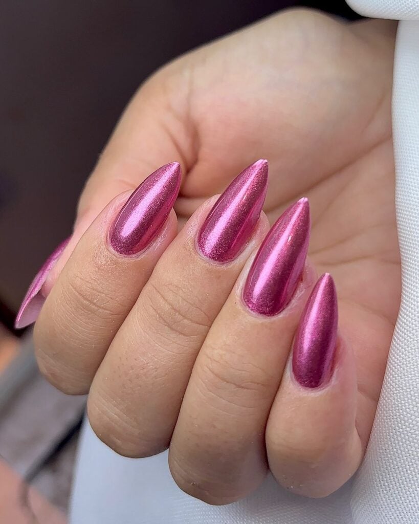 Mão de pele branca com unha longa stiletto rosa metálica 
