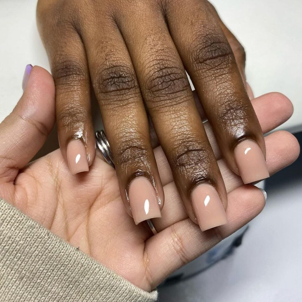 Mão de pele preta com unha quadrada nude 