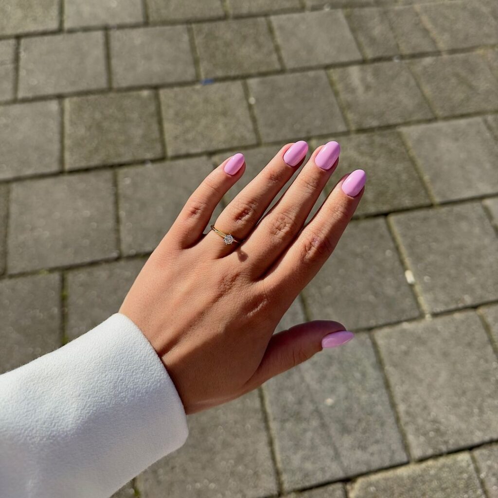 Mão de pele branca, com anel e unha amendoada rosa pastel 