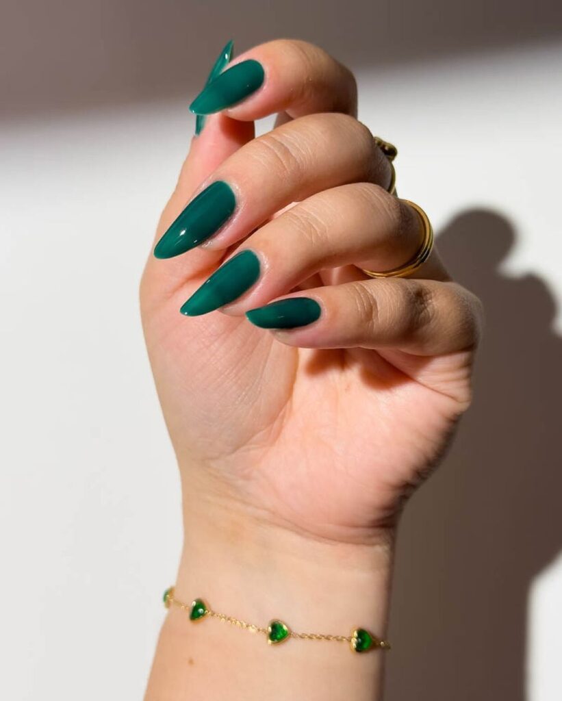 Mão de pele branca com unha amendoada verde-esmeralda 