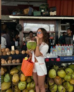 Mulher jovem e magra bebendo água de coco
