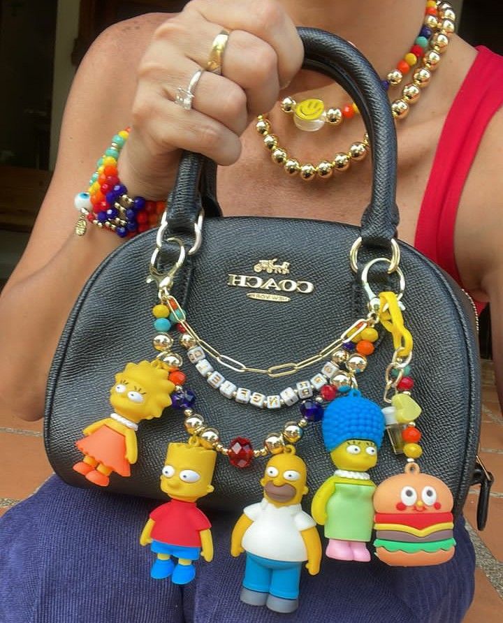 Mulher segurando bolsa preta com vários pingentes dos simpsons