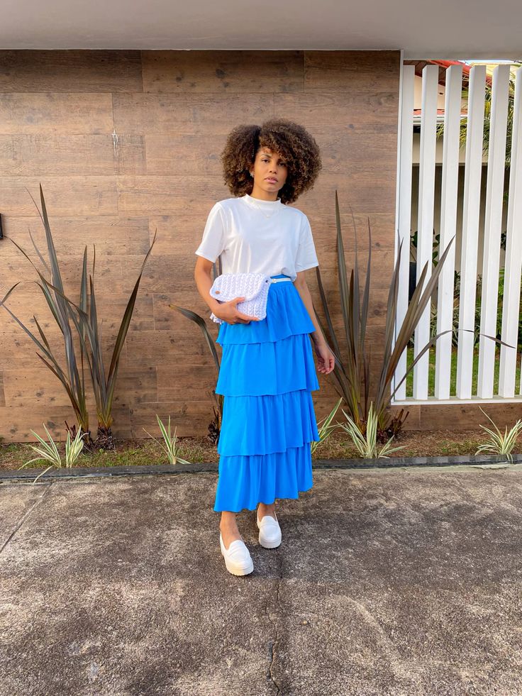 Mulher usando camiseta branca e saia três marias na cor azul