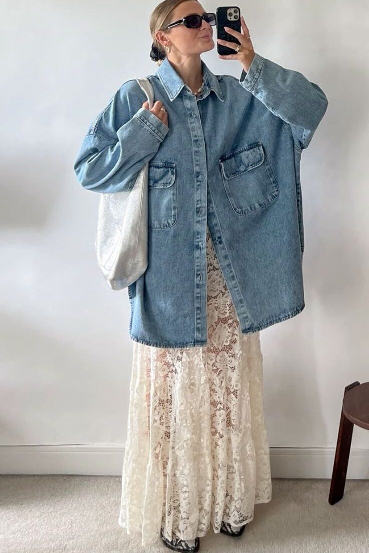 Mulher jovem e magra com pele clara e cabelos loiros. Ela usa camisa jeans longa e saia de renda.