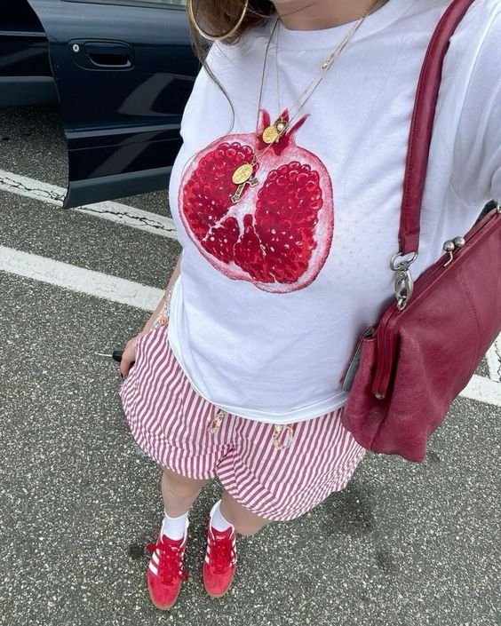 Tronco de mulher magra de pele clara. Ela está usando uma camiseta com estampa de fruta.