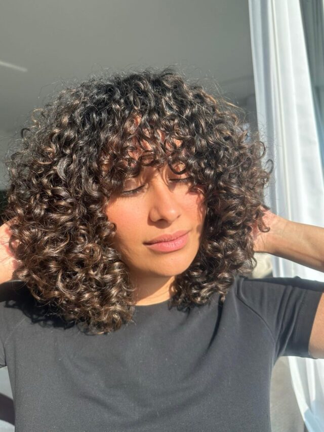 Mulher com corte de cabelo cacheado e com franja
