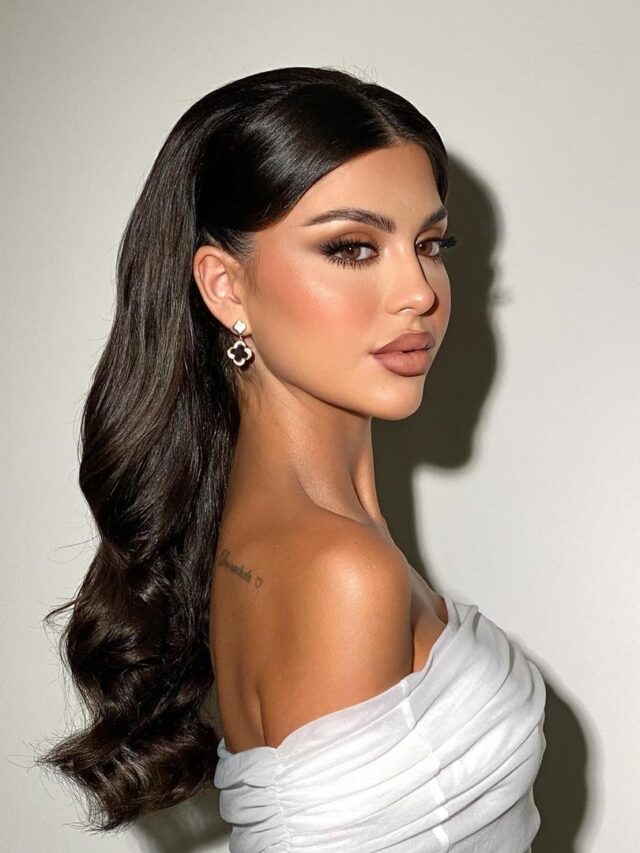 Mulher de pele branca, com vestido tomara que caia branco, cabelo meio preso e maquiagem chique