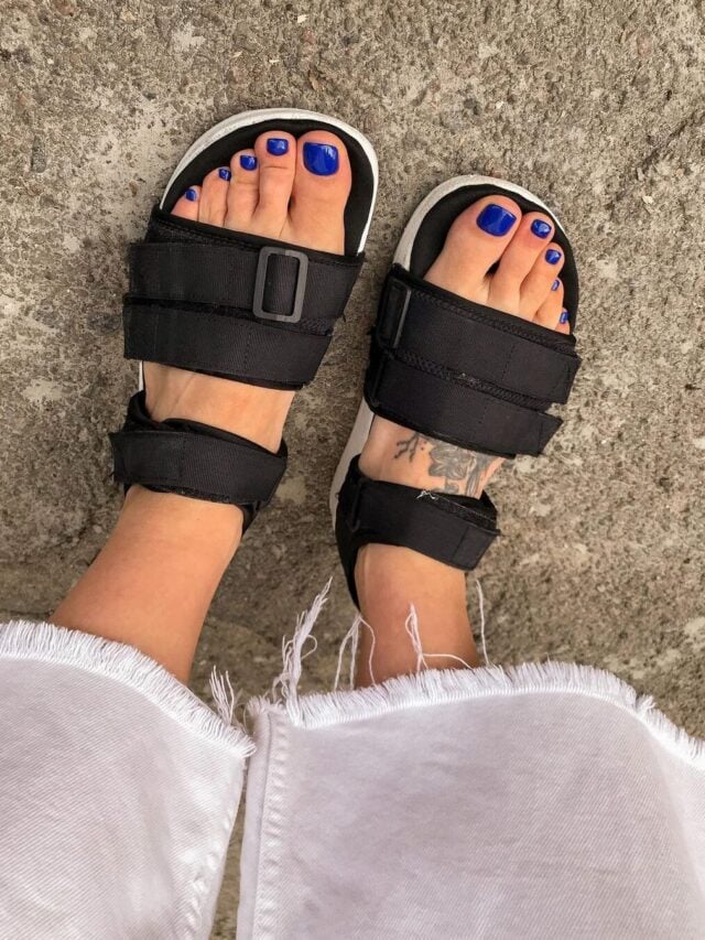 Pés de pele branca, em sapado de tiras preto, com unha azul