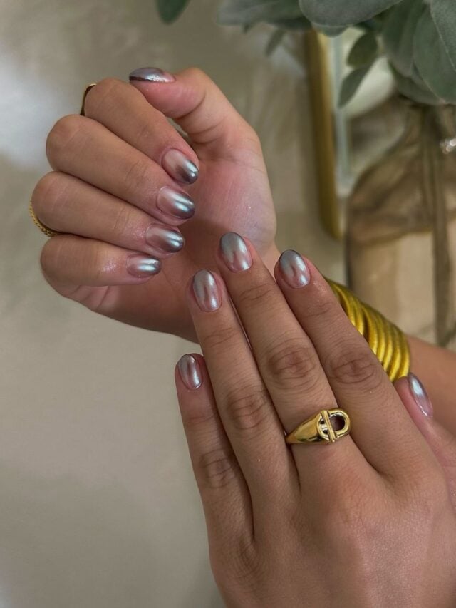 Mãos de pele branca, com anel dourado e unha curta redonda ombré