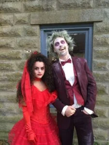 Casal com fantasia de halloween. Eles estão vestidos de Beetlejuice e Lydia.