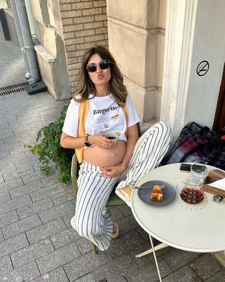 Mulher jovem e magra com pele clara. Ela usa camiseta e calça listrada.